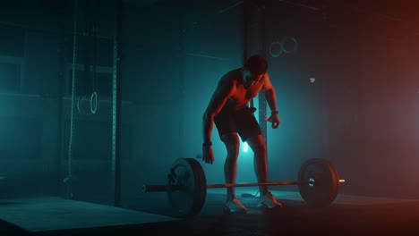 Muscular-fitness-man-doing-push-a-barbell-over-his-head-in-modern-fitness-center.-Functional-training.-Snatch-exercise.-Slow-motion-color-LED-light-saturated-bright-colors
